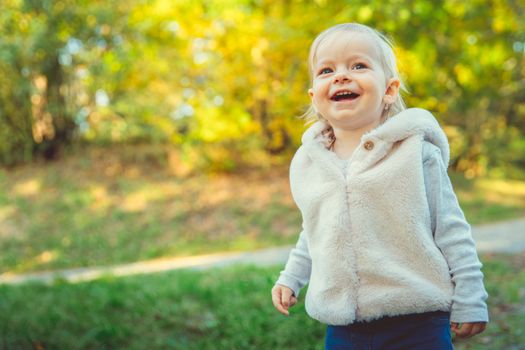 Happy children rejoices autumn weather and playing in the meadow in the park