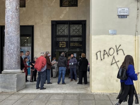 Greeks keep their distance outside bank entrance, in line with government decision to prevent COVID-19.
