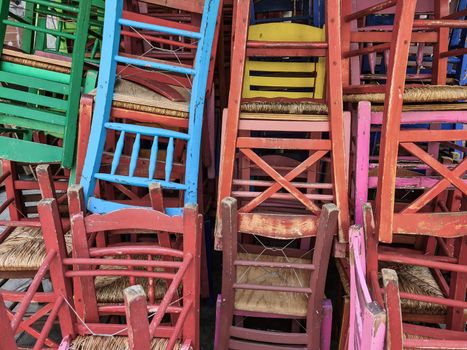 Day sunny view of tavern style chairs in random disarray and bright colours in Greece.