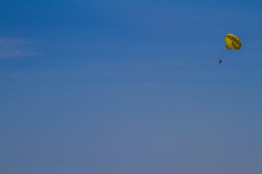 A person para-sailing in the sunshine at a beach