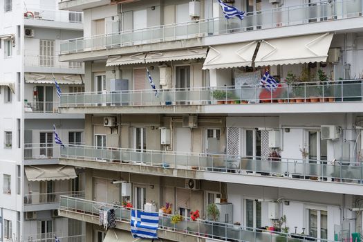 Blue and white Greek flags with cross outside city homes, celebrating the March 25 1821 day of Greek War of Independence.