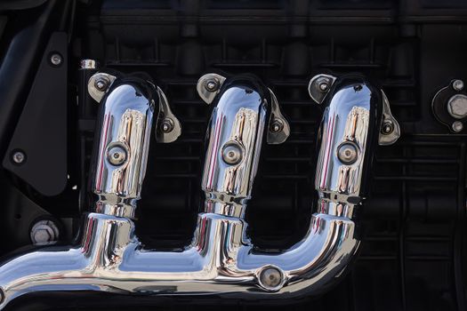Three chromed exhaust pipes connecting to one of the motorcycle engine