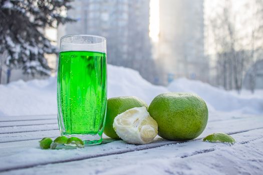 Fresh juice in a glass and citrus fruits stand outside on a winter morning