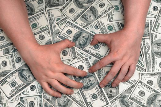 Hands lie on top of a huge pile of hundred-dollar bills