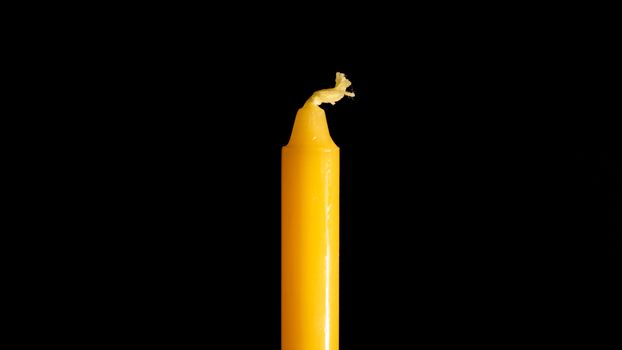 A close up of a yellow candle in a black background