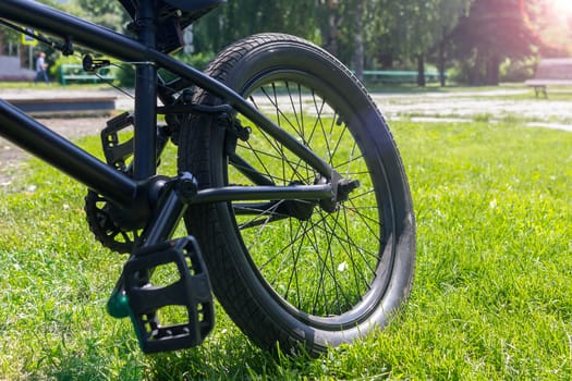 Sport bike parked on grass lawn in a city, public park. Bicycle rear wheel