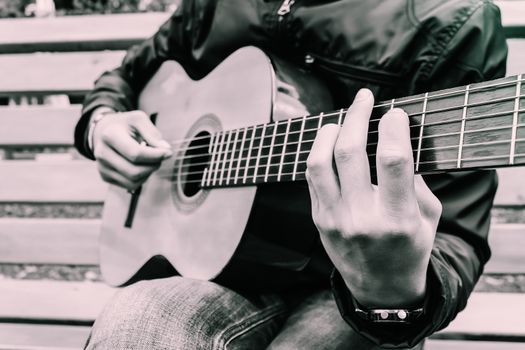 The musician beautifully plays his beautiful guitar and close-up fingerboard with strings clamped by his fingers