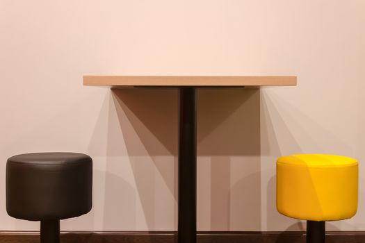 Table and chairs and the shadows falling from them against the background of the wall in light bed colors. Shadows create many triangles on the wall