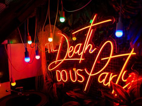Red neon lettering on a contrasting black background. And colorful light bulbs. High quality photo