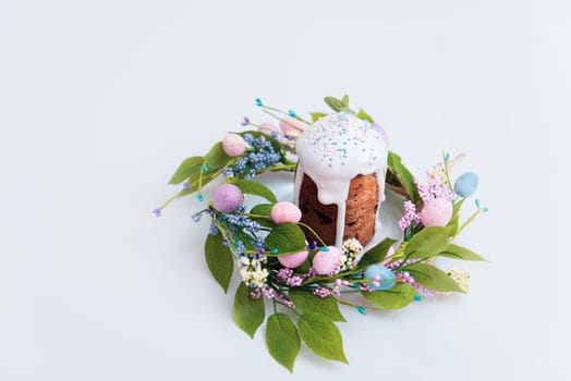 Easter cake in the center of a wreath of spring flowers on a white background