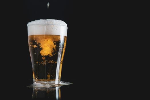 foam beer poured into a glass on a black background with copy space