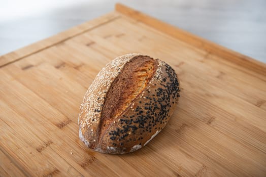 craft bread is sprinkled with white and black sesame seeds on a wooden background with empty place for text