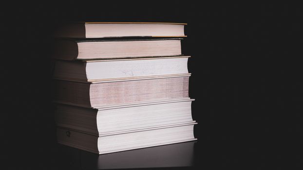 High stack of books on a black background