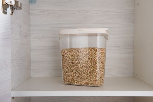 buckwheat in a transparent cereal container located in the shelf of the closet