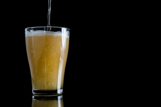 foam beer poured into a glass on a black background