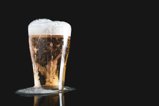 foam beer poured from a glass on a black background with copy space