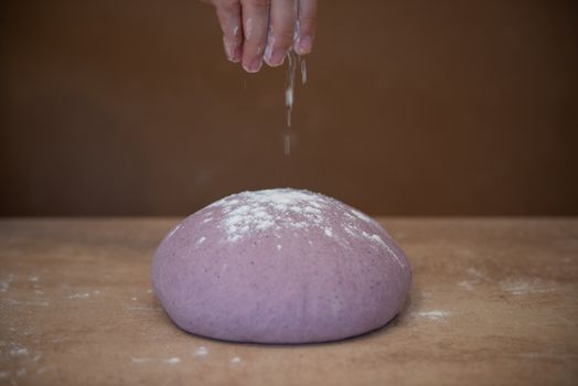 Preparation for bread unusual lilac-colored dough on a brown background