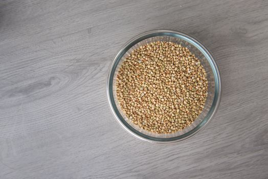 buckwheat in a glass bowl on a wooden light table with copy space