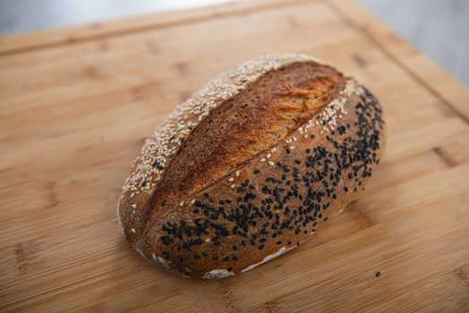 craft bread is sprinkled with white and black sesame seeds on a wooden background with empty place for text