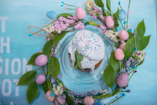 Easter cake in the center of a wreath of spring flowers on a blue vintage background