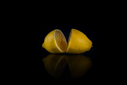 two halves of whole lemon on a black background with copy space