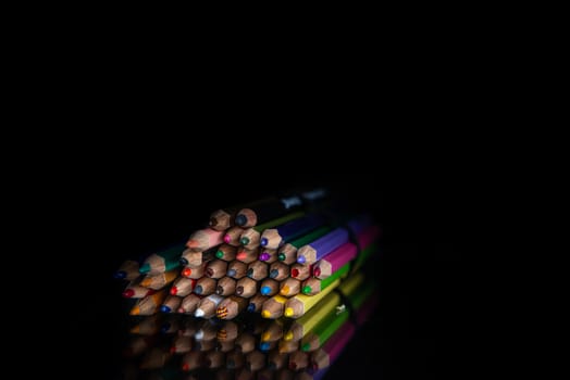 stack of colored pencils on a black background