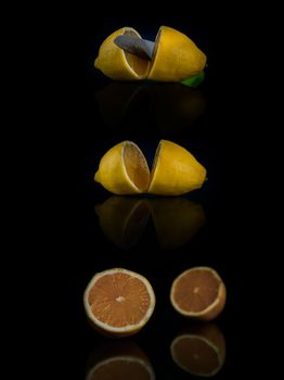 two halves of lemon cut with a knife on a black background with copy space