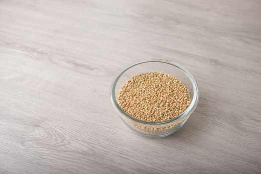 buckwheat in a glass bowl on a wooden light table with copy space