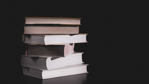 messy stack of books on a black background