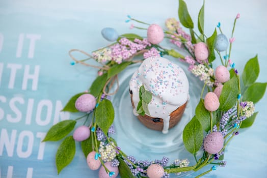 Easter cake in the center of a wreath of spring flowers on a blue vintage background