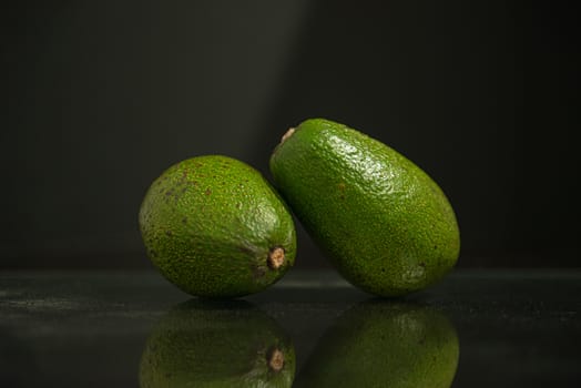 Group of two whole avocados on a black background