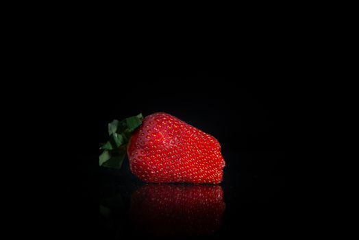 fresh strawberries on a black background with reflection