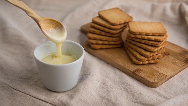 bowl with condensed milk and biscuits in the background