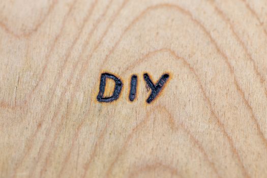 an abbreviation DIY - do it yourself - burned by hand with electrical woodburner on plywood surface.