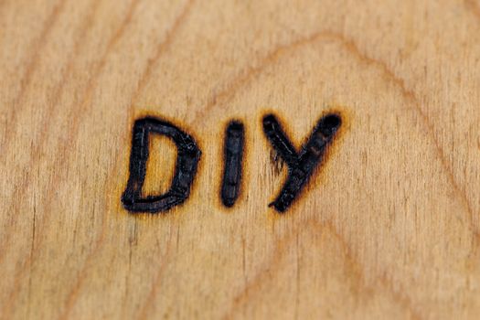 an abbreviation DIY - do it yourself - burned by hand with electrical woodburner on plywood surface.