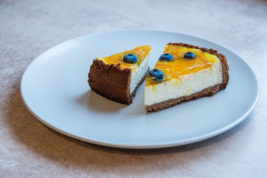 Two piece of homemade cake on grey plate with berry decorate on top