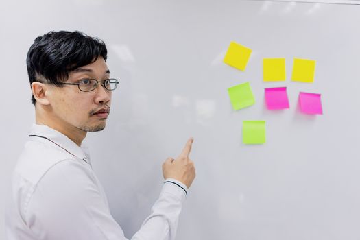 A business man pointing his hand to the board with notes