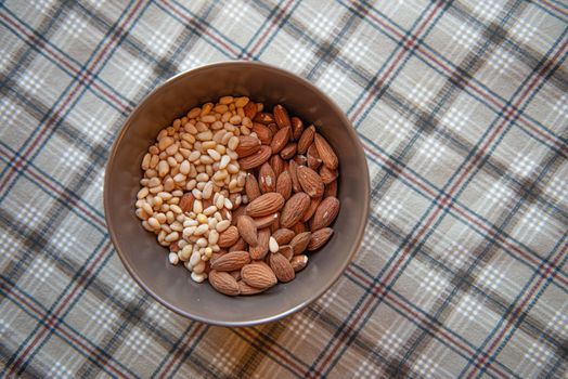 Pine and almond nuts in a brown deep plate on a checkered tablecloth