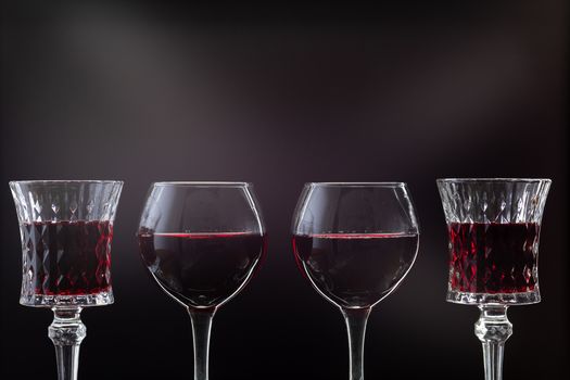Rose wine. Red wine in four wine glasses over dark background with rays of light.