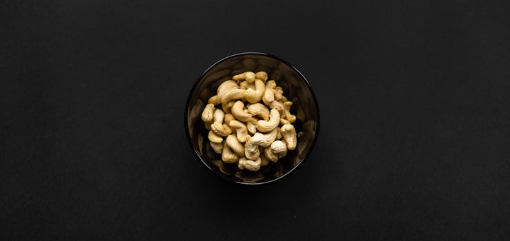 Cashew nuts in a small plate on a black table as a background. Cashew nut is a healthy vegetarian protein nutritious food
