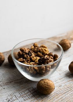 Walnut in a smale plate with scattered shelled nuts and whole nut which standing on a wooden vintage table. Walnuts is a healthy vegetarian protein nutritious food. Walnut on rustic old wood