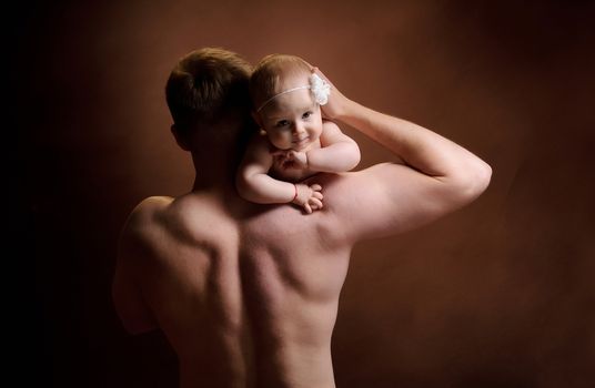 Male holding nice infant baby girl. Daughter on father's shoulders. Human growth and development. New generation. Cheerful man and his baby. New life concept. Dark background