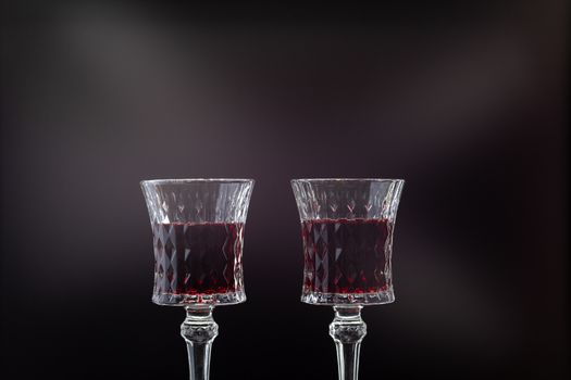 Rose wine. Red wine in two wine glasses over dark background with rays of light.