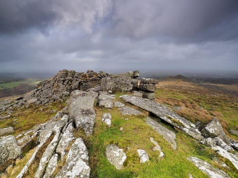 View from Belstone Tor looking down over the countryside set under a dark brooding stormy sky, Dartmoor National Park, Devon, UK