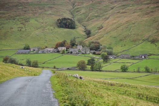 Looking down the road to the picturesque village of Halton Gill nestling in the hillside, Yorkshire Dales, UK