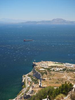 View from the top of the Rock of Gibraltar across the Strait of Gibraltar with passing container ship and Morocco in the distance