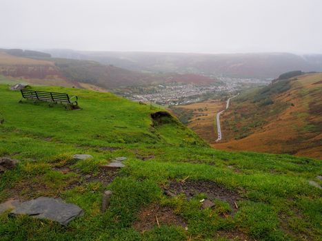 View of Treorchy on a misty wet day with solitary bench overlooking road winding off into the valley, Rhondda Cynon Taf, Mid Glamorgan, South Wales