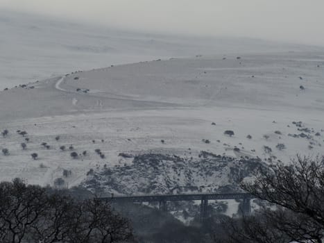 Meldon viaduct in the snow with Longstone Hill in the background, Dartmoor National Park, Devon, UK