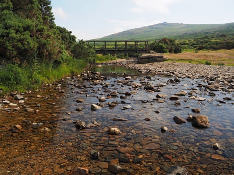 Footbridge over the River Lyd with crystal clear water and rocks, Dartmoor National Park, Devon, UK