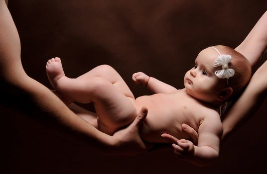 Male and female holding nice infant baby girl. Daughter on father's and mother's arms. Human growth and development. New generation. New life concept